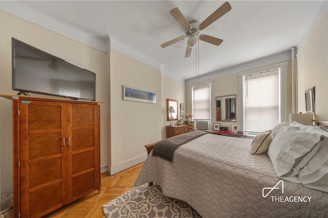 bedroom with cooling unit, ceiling fan, and light parquet flooring