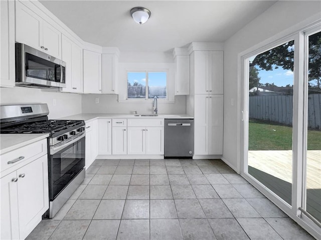 kitchen with stainless steel appliances, white cabinetry, and plenty of natural light