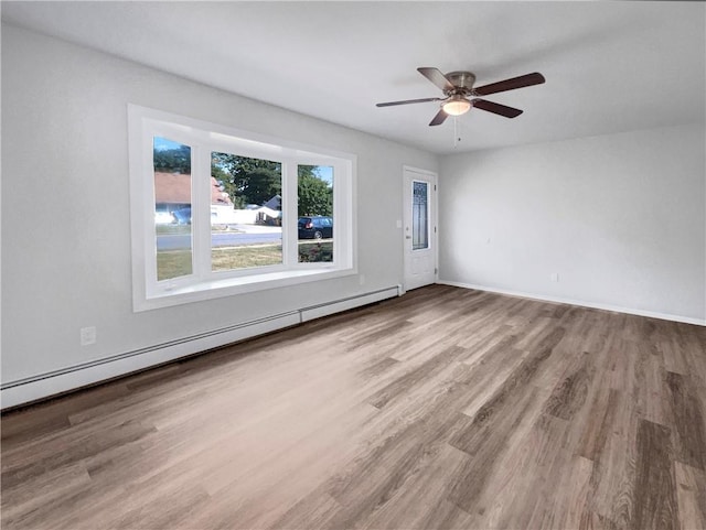 spare room with ceiling fan, wood-type flooring, and a baseboard heating unit