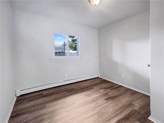 empty room featuring baseboard heating and dark hardwood / wood-style floors