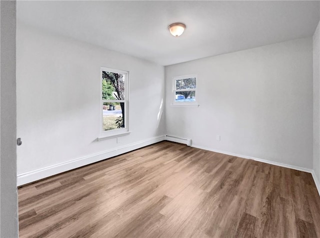 unfurnished room featuring hardwood / wood-style flooring, a healthy amount of sunlight, and a baseboard radiator