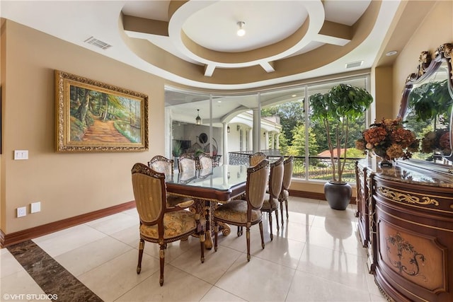 tiled dining area featuring a raised ceiling