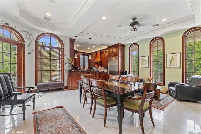 tiled dining room featuring a tray ceiling, ceiling fan, and crown molding