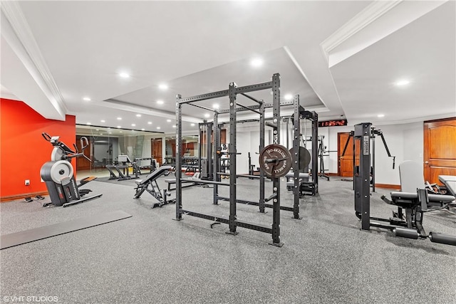 workout area featuring a raised ceiling and crown molding