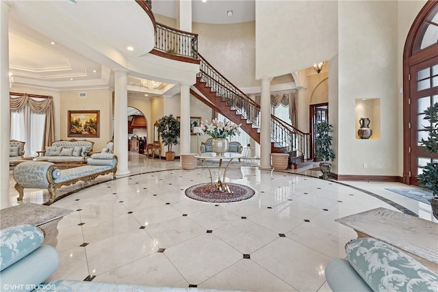 tiled entryway with ornate columns, crown molding, and a high ceiling