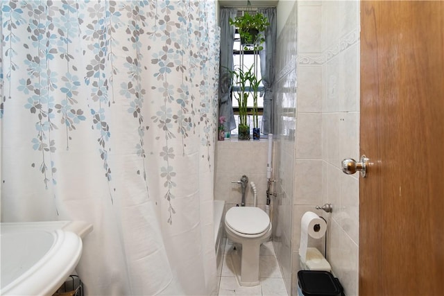 bathroom with sink, a shower with curtain, tile patterned floors, toilet, and tile walls