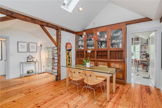 dining space with vaulted ceiling with skylight and light hardwood / wood-style floors