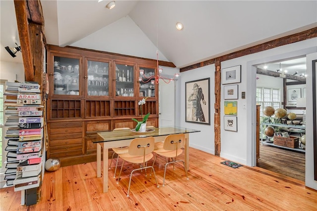 dining room with light wood-type flooring, lofted ceiling, and an inviting chandelier