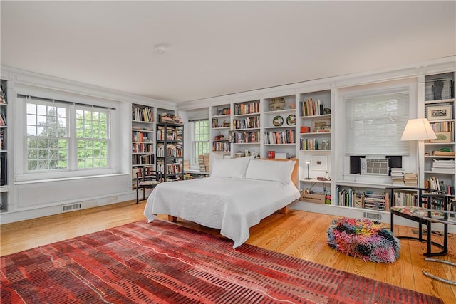 bedroom with hardwood / wood-style floors, cooling unit, and crown molding