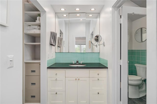 bathroom with vanity, tile walls, and toilet