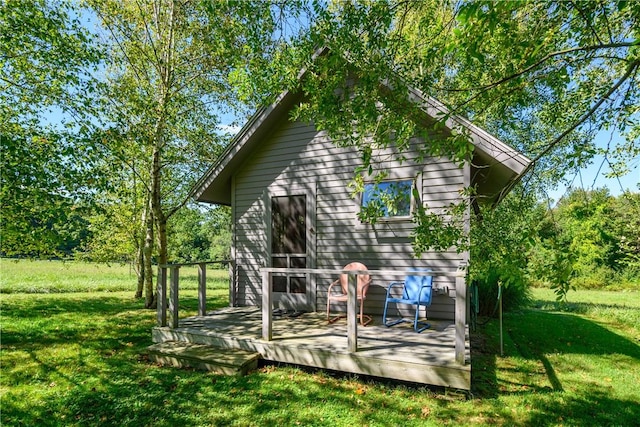 rear view of house featuring a wooden deck and a lawn