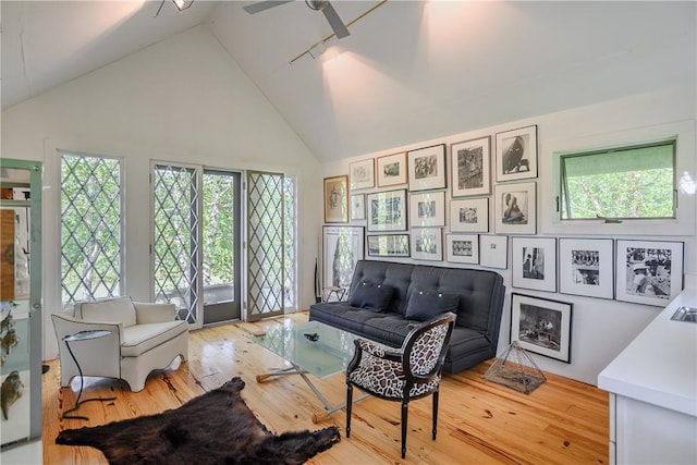 living room with plenty of natural light, wood-type flooring, and high vaulted ceiling