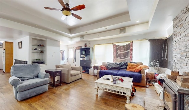 living room featuring hardwood / wood-style flooring, ceiling fan, and a raised ceiling