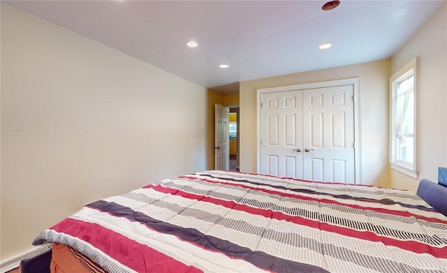 bedroom featuring multiple windows, a closet, and a baseboard heating unit