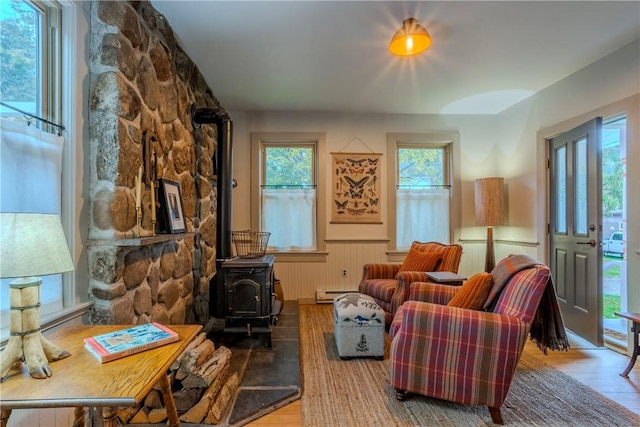 living room featuring hardwood / wood-style flooring, a wood stove, and a baseboard heating unit