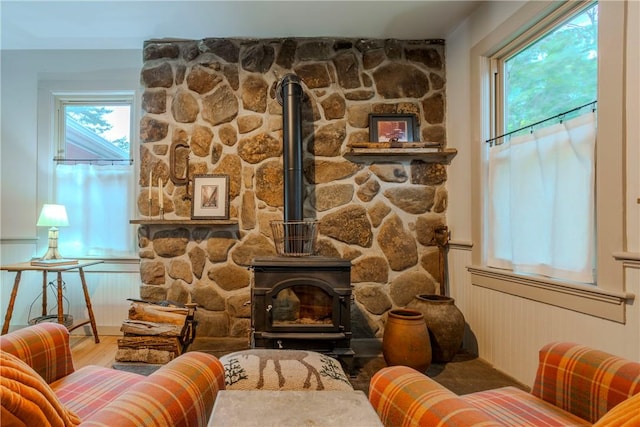 sitting room with hardwood / wood-style floors, a healthy amount of sunlight, and a wood stove