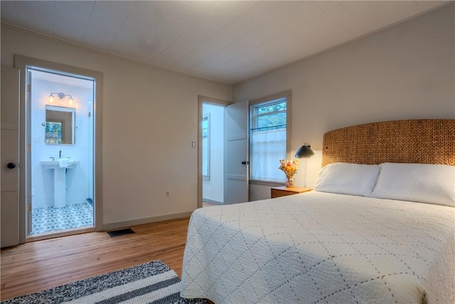 bedroom featuring connected bathroom and wood-type flooring