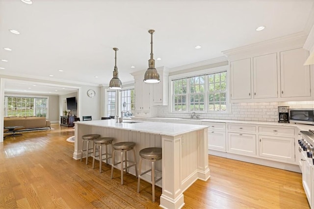 kitchen with a sink, white cabinetry, a center island, tasteful backsplash, and stainless steel microwave