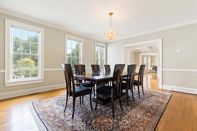 dining area with wood finished floors, visible vents, baseboards, ornamental molding, and an inviting chandelier