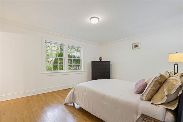 bedroom with baseboards, crown molding, and wood finished floors