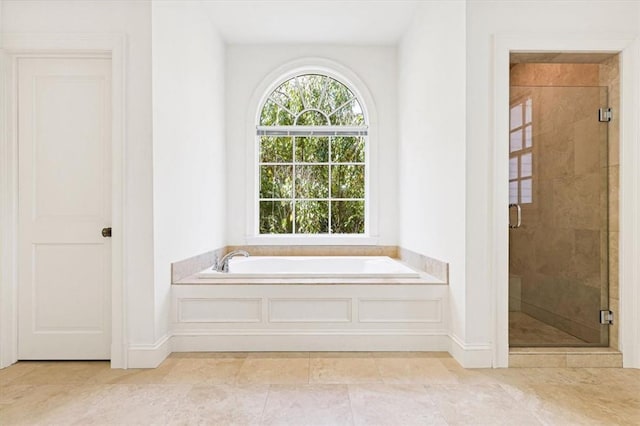 bathroom featuring a shower stall, baseboards, and a bath