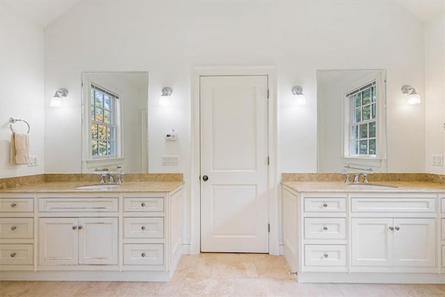 full bath featuring plenty of natural light, two vanities, and a sink