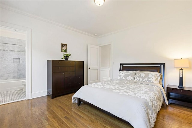 bedroom featuring baseboards, wood finished floors, connected bathroom, and crown molding