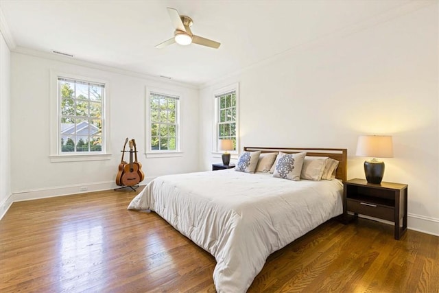 bedroom with crown molding, multiple windows, baseboards, and wood finished floors