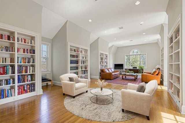 living area featuring built in shelves, recessed lighting, baseboards, and wood finished floors