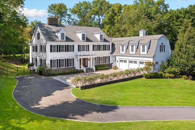 view of front of property featuring driveway, a chimney, an attached garage, fence, and a front yard