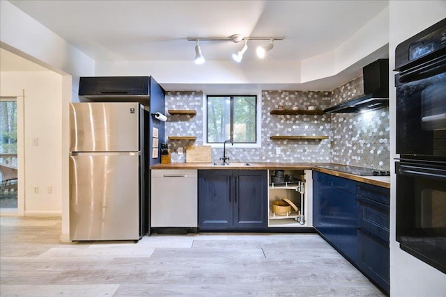 kitchen featuring wood counters, black appliances, sink, light hardwood / wood-style flooring, and decorative backsplash