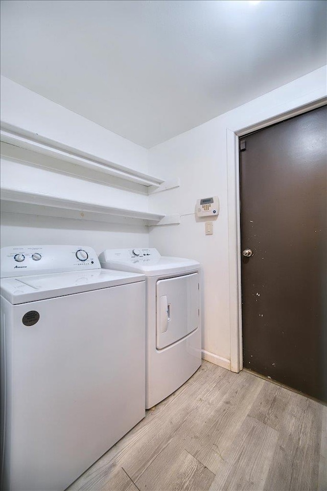 laundry area with separate washer and dryer and light hardwood / wood-style flooring