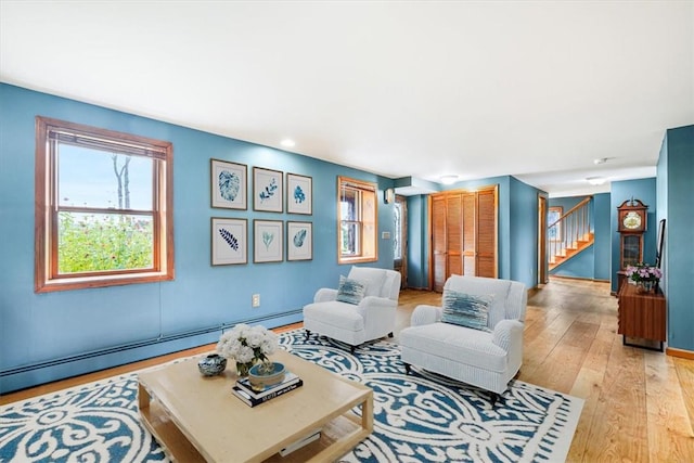 living room with baseboard heating and light hardwood / wood-style floors