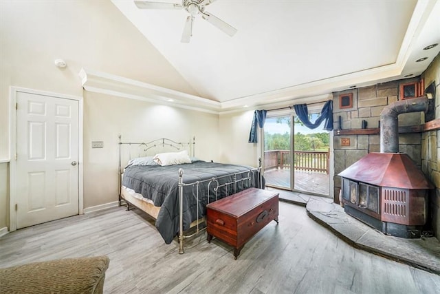 bedroom with a wood stove, ceiling fan, access to exterior, high vaulted ceiling, and wood-type flooring