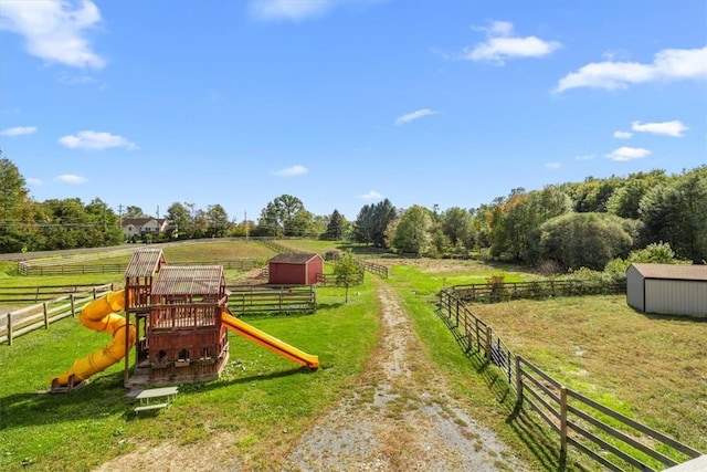 view of yard featuring a playground, a rural view, and a shed