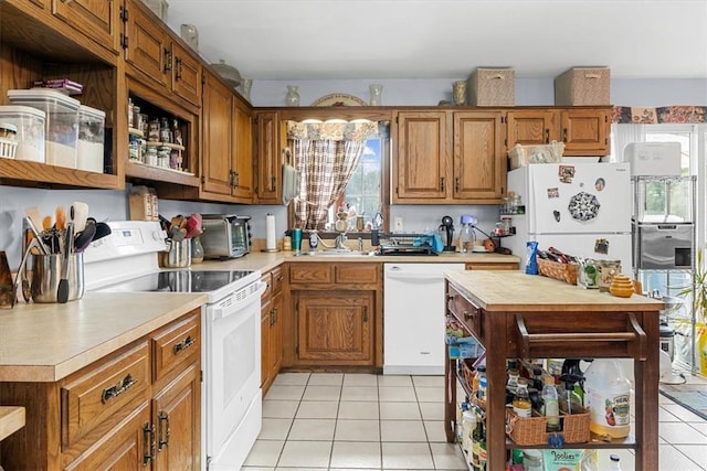 kitchen with white appliances, plenty of natural light, sink, and light tile patterned floors