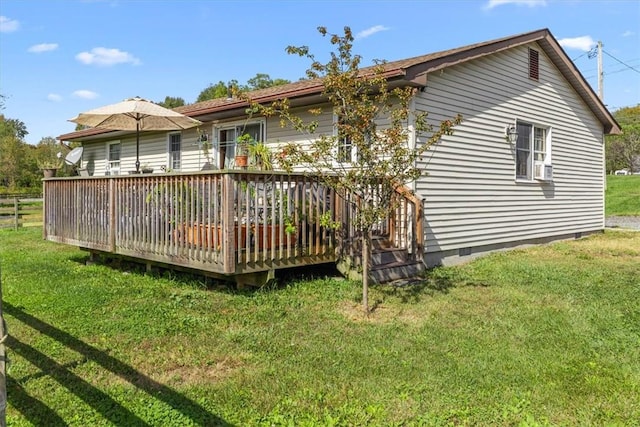 rear view of property featuring a wooden deck and a lawn