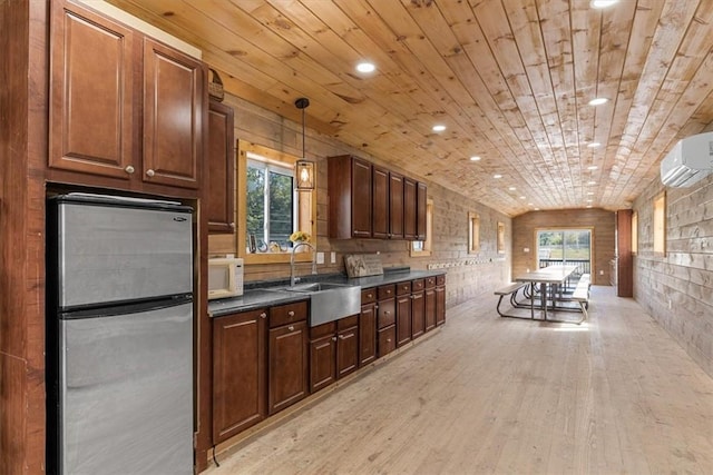 kitchen featuring hanging light fixtures, brick wall, sink, and stainless steel fridge