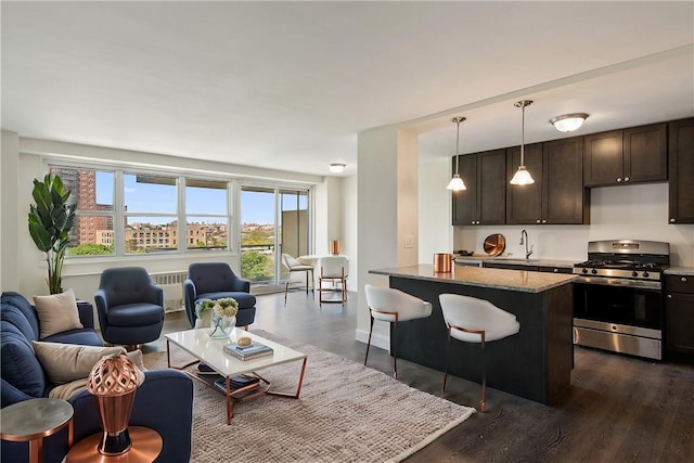 kitchen with dark hardwood / wood-style flooring, light stone countertops, hanging light fixtures, and stainless steel gas range