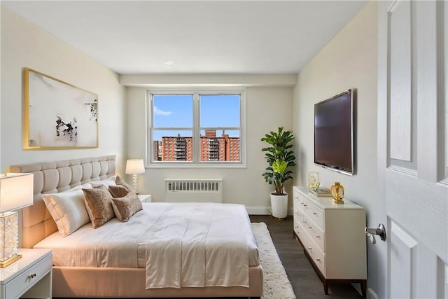 bedroom with radiator heating unit and dark hardwood / wood-style flooring