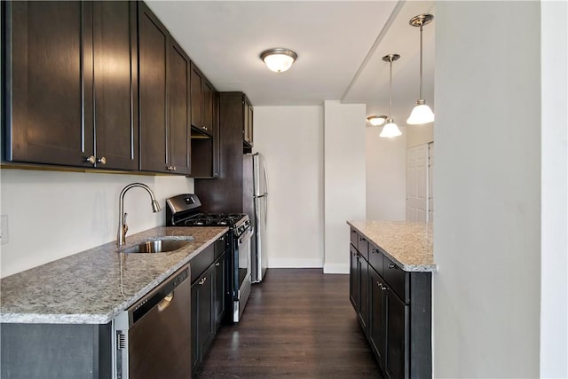 kitchen featuring pendant lighting, dark wood-type flooring, light stone countertops, appliances with stainless steel finishes, and dark brown cabinets