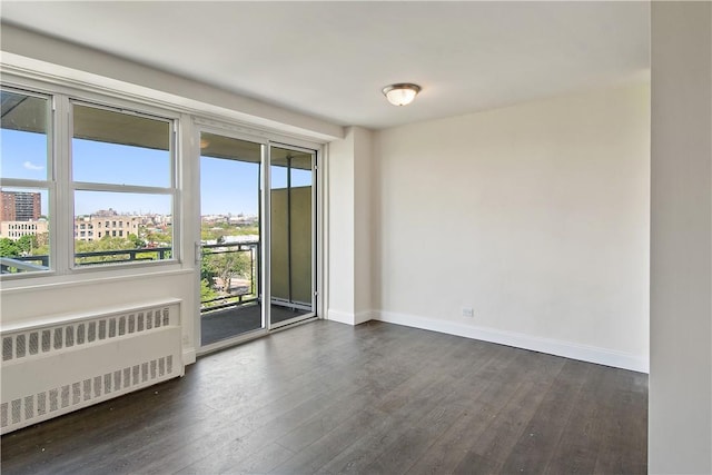 unfurnished room with radiator heating unit and dark hardwood / wood-style flooring