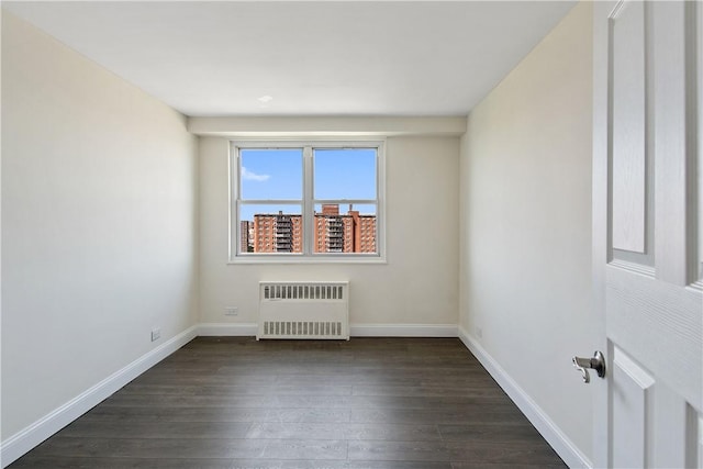 spare room featuring dark hardwood / wood-style floors and radiator