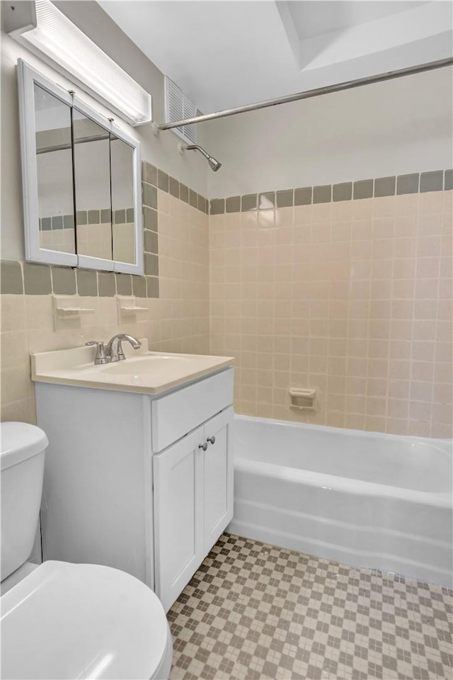 full bathroom with vanity, toilet, tile walls, and tiled shower / bath combo