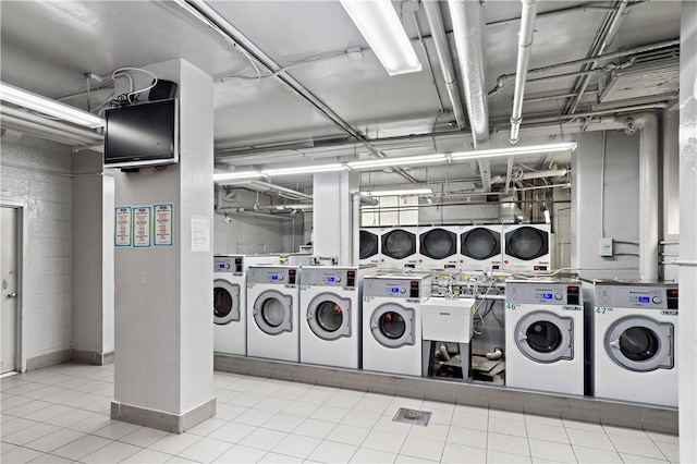 laundry room with light tile patterned floors, sink, stacked washing maching and dryer, and washing machine and clothes dryer