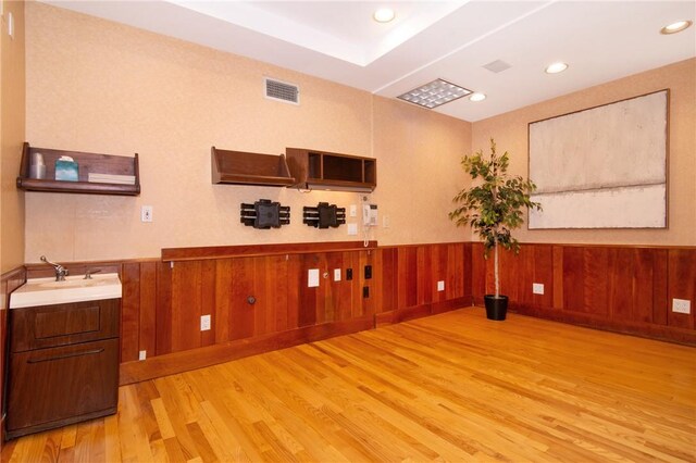 interior space with wood walls, light hardwood / wood-style flooring, and sink