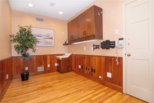 interior space featuring light wood-type flooring and wooden walls