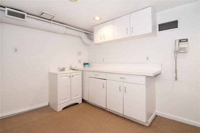 kitchen with light carpet, sink, and white cabinets