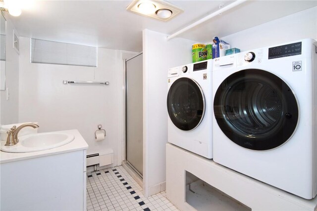 clothes washing area with light tile patterned floors, washing machine and dryer, a baseboard radiator, and sink