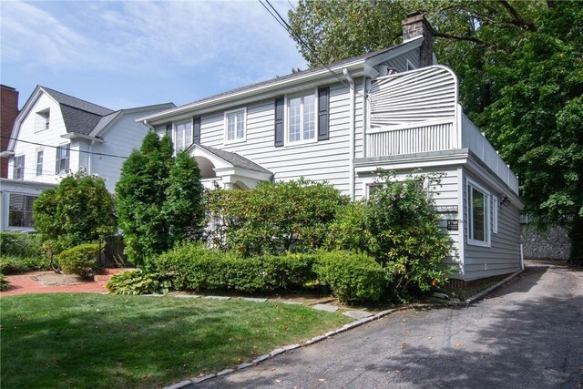 view of front of house featuring a balcony and a front lawn